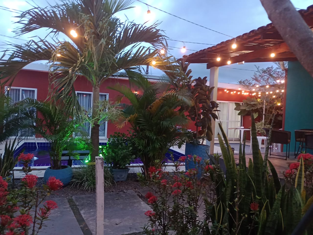 Jardim tropical iluminado da Casa Bella Eventos ao entardecer